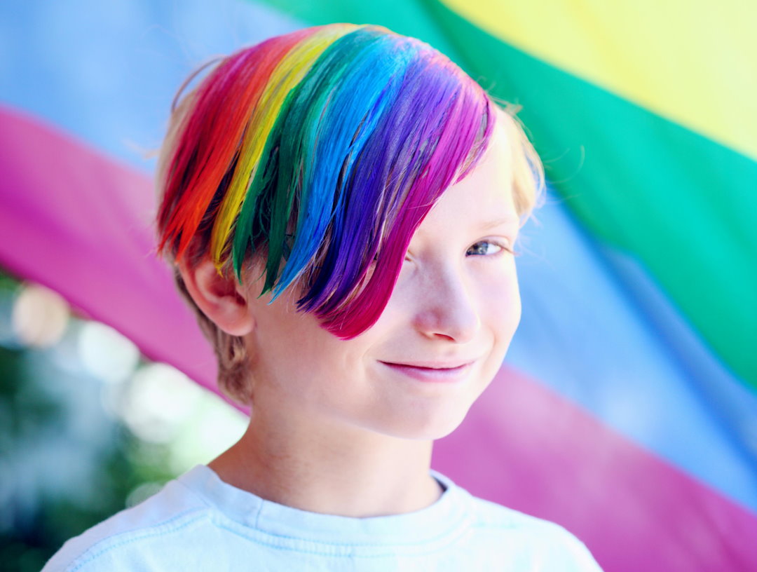 Foto eines Teenagers mit Strähnen in Regenbogenfarben.
