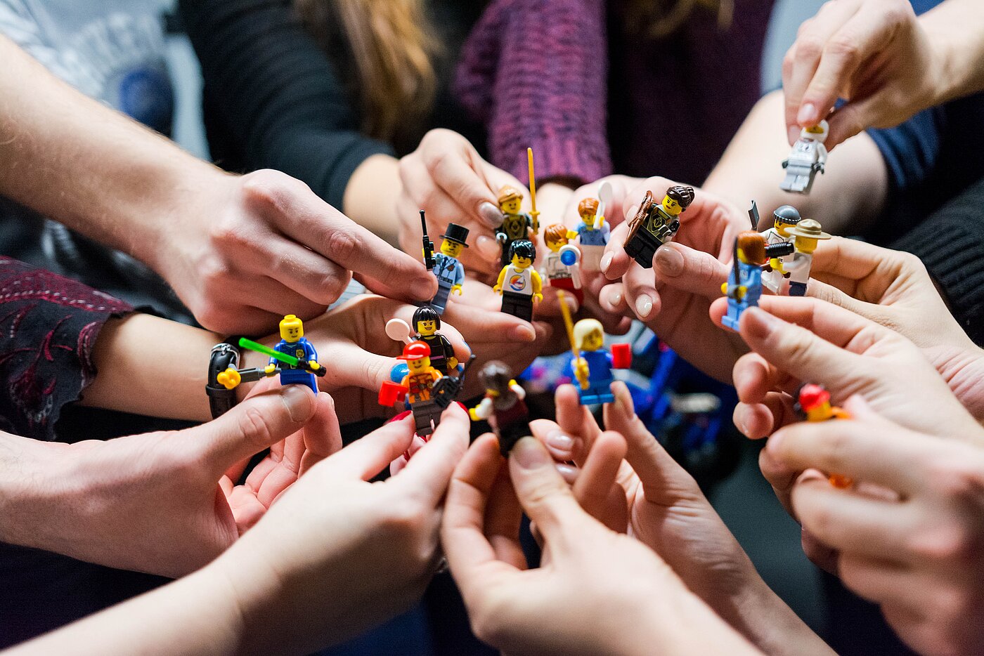 Das Bild zeigt Hände die Legofiguren halten.
