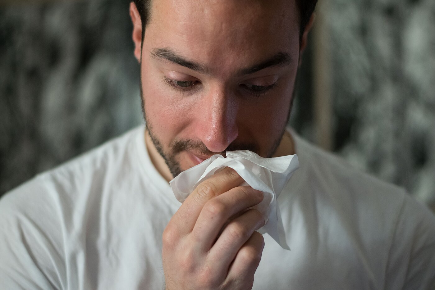 Foto von einem Mann, der seine Nase putzt.