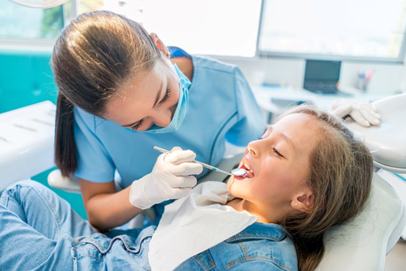 Das Foto zeigt eine Zahnärztin bei der Behandlung eines Kindes.